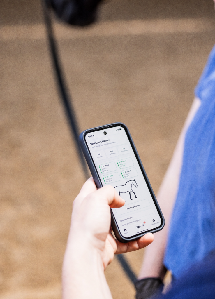 Person hält ein Smartphone mit geöffneter CALVARA-App zur Vorbereitung einer Ganganalyse beim Pferd.